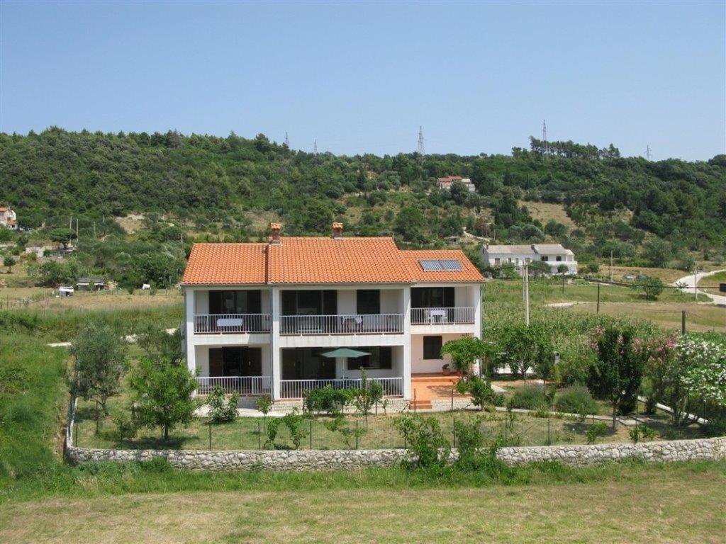 a house with an orange roof on a hill at Apartments with a parking space Palit, Rab - 16356 in Mundanije