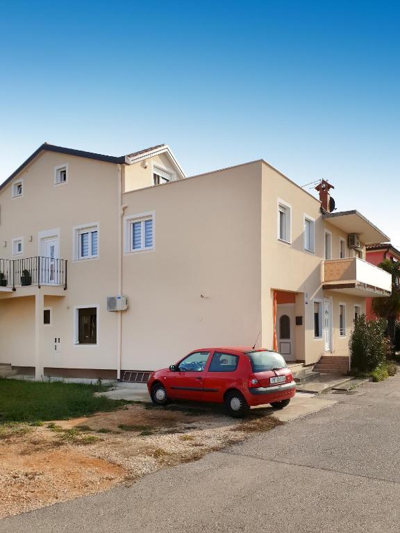czerwony samochód zaparkowany przed budynkiem w obiekcie Apartments with a parking space Umag - 16354 w mieście Umag