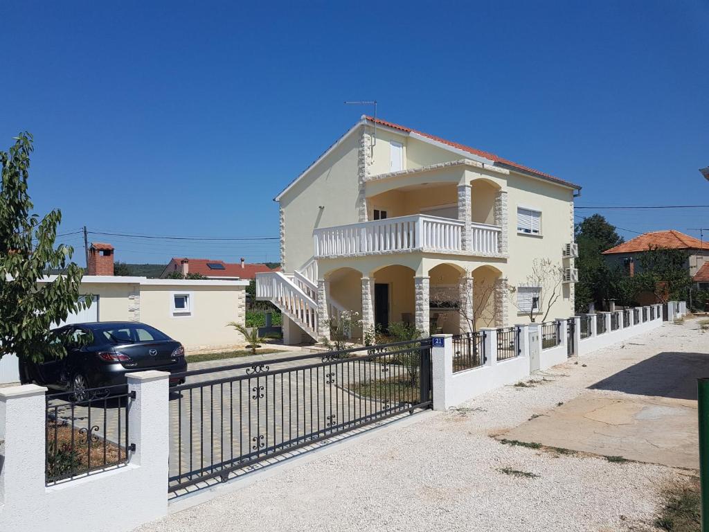 une maison blanche avec un portail et une voiture dans l'établissement Holiday house with a parking space Sukosan, Zadar - 16398, à Sukošan