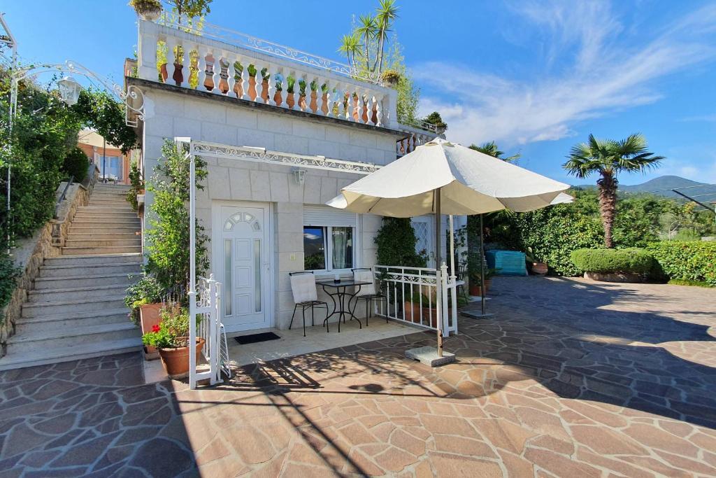 taras z parasolem i stołem z krzesłami w obiekcie Family friendly apartments with a swimming pool Lovran, Opatija - 14178 w mieście Lovran