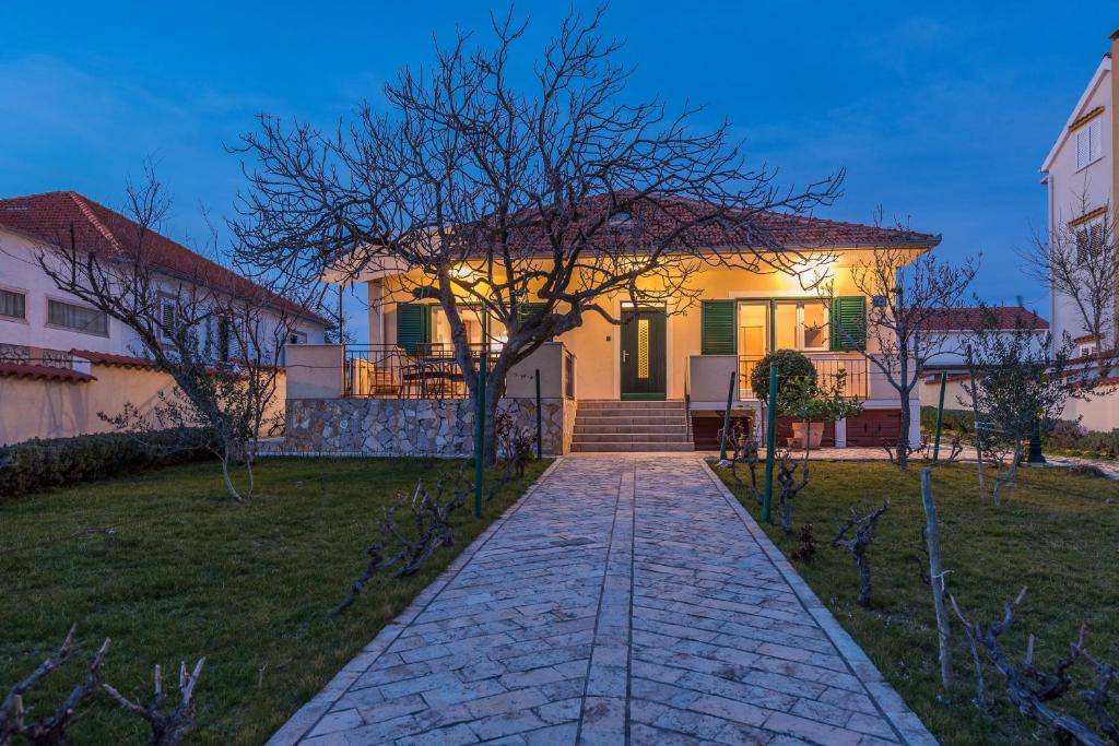 a house with a walkway in front of a yard at Holiday house with a parking space Vrsi - Mulo, Zadar - 16527 in Vrsi