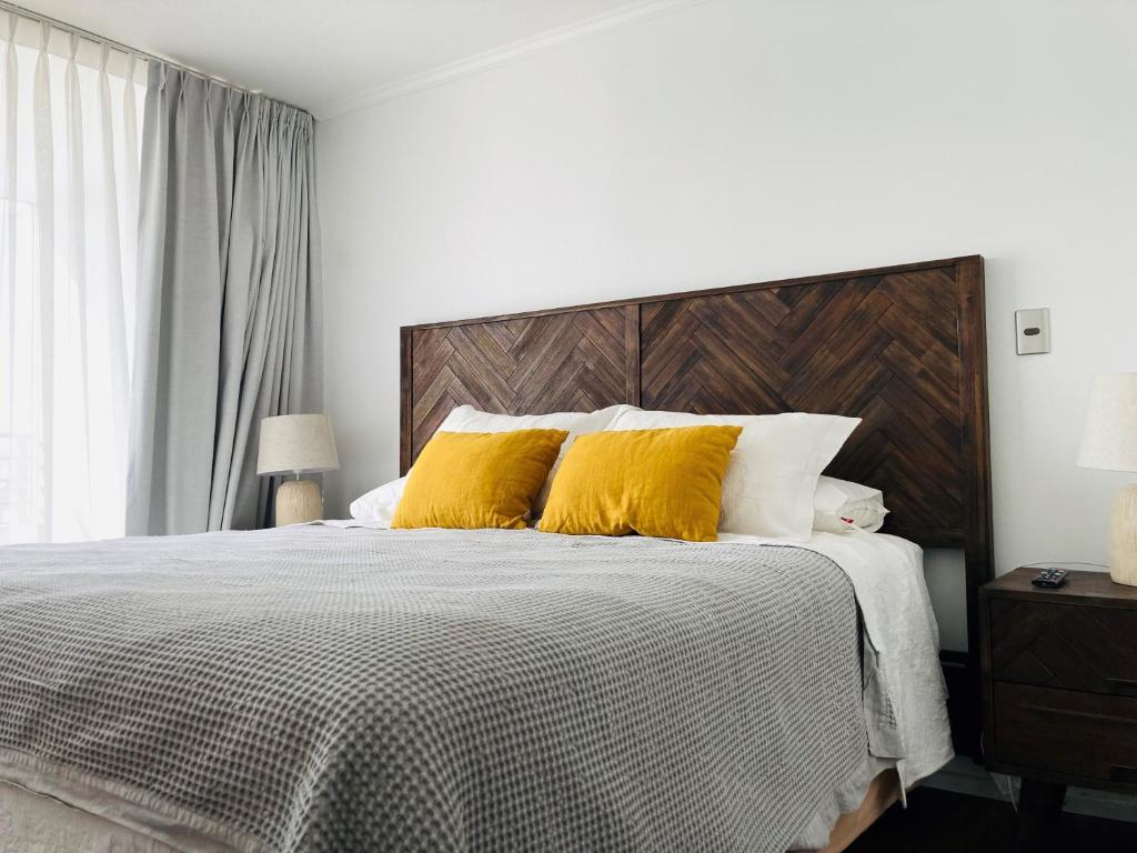 1 dormitorio con 1 cama con 2 almohadas amarillas en Alta Vista Las Condes en Santiago