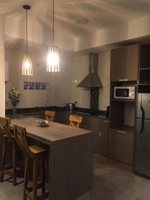 a kitchen with a kitchen island with chairs and a refrigerator at Plano Vertical in San Miguel de Tucumán