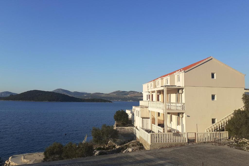 a large white building next to a body of water at Apartments by the sea Cove Pjestata, Peljesac - 14440 in Ston