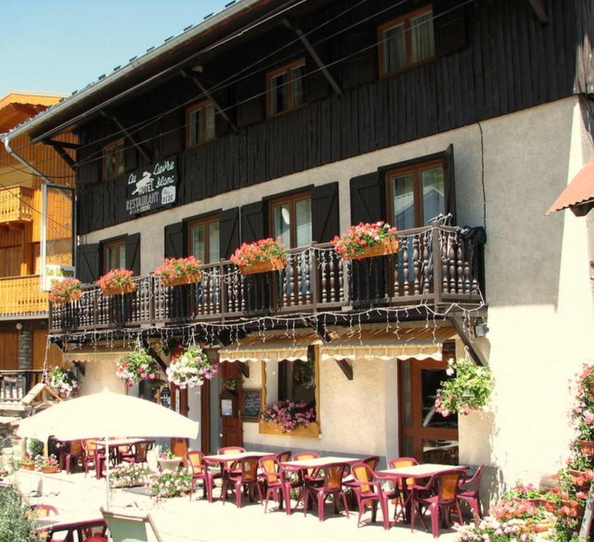 un restaurant avec des tables et des chaises en face d'un bâtiment dans l'établissement Hôtel Le Lievre Blanc, à Vars