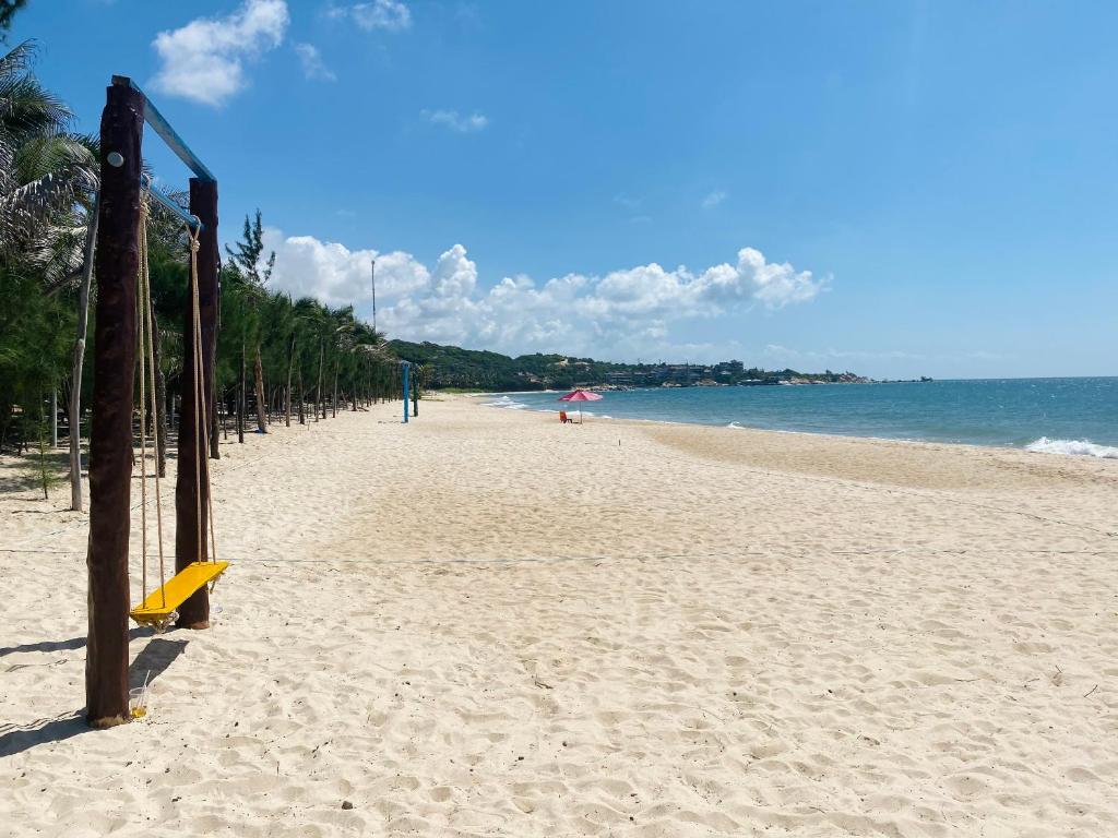 a sandy beach with an umbrella and the ocean at Kega Lighthouse Resort Bình Thuận in Ke Ga