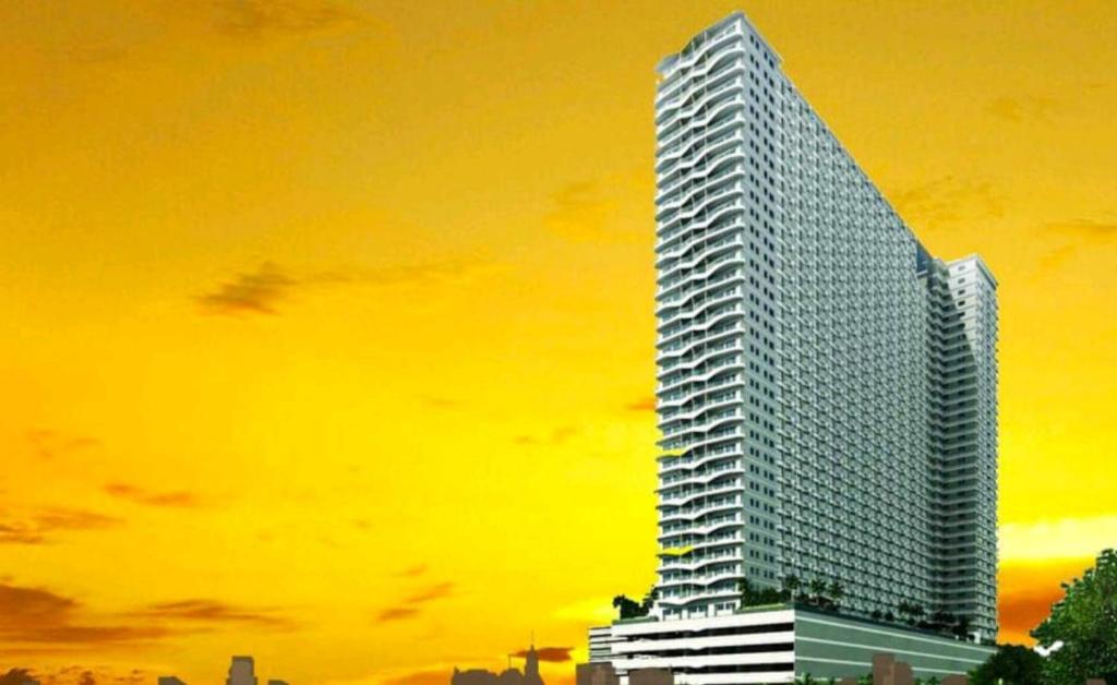 un edificio alto con un cielo amarillo en el fondo en Jk Coastal Inn, en Manila