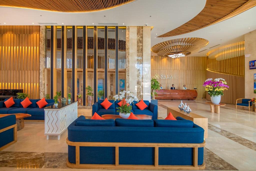 A warmly lit lobby with blue seating, orange cushions and a staffed reception desk.