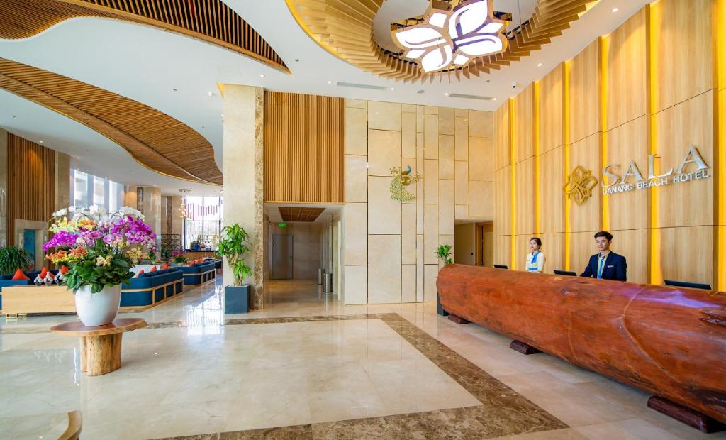The reception area pairs a long wood-fronted desk with a bright, high-ceilinged lobby.