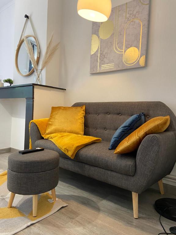 sala de estar con sofá gris y almohadas amarillas en Le Petit Gayant, en Douai