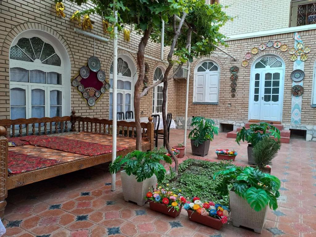 une terrasse couverte d'une maison avec un banc et des arbres dans l'établissement Parivash Guest House, à Boukhara