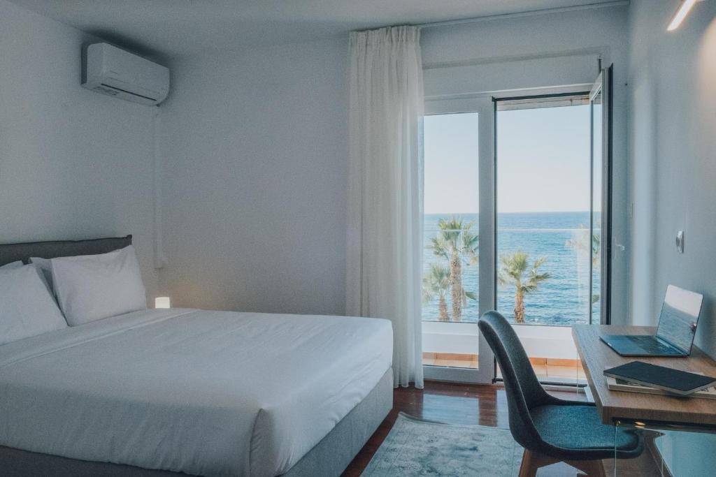 1 dormitorio con cama, escritorio y ventana en Suitenes Coast en Rethymno