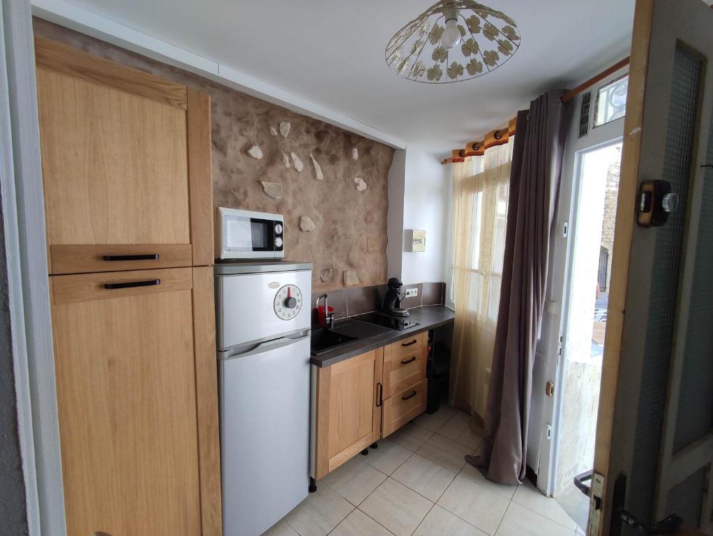 La cuisine est équipée d'un réfrigérateur blanc et d'un four micro-ondes. dans l'établissement Cueva, à Arles