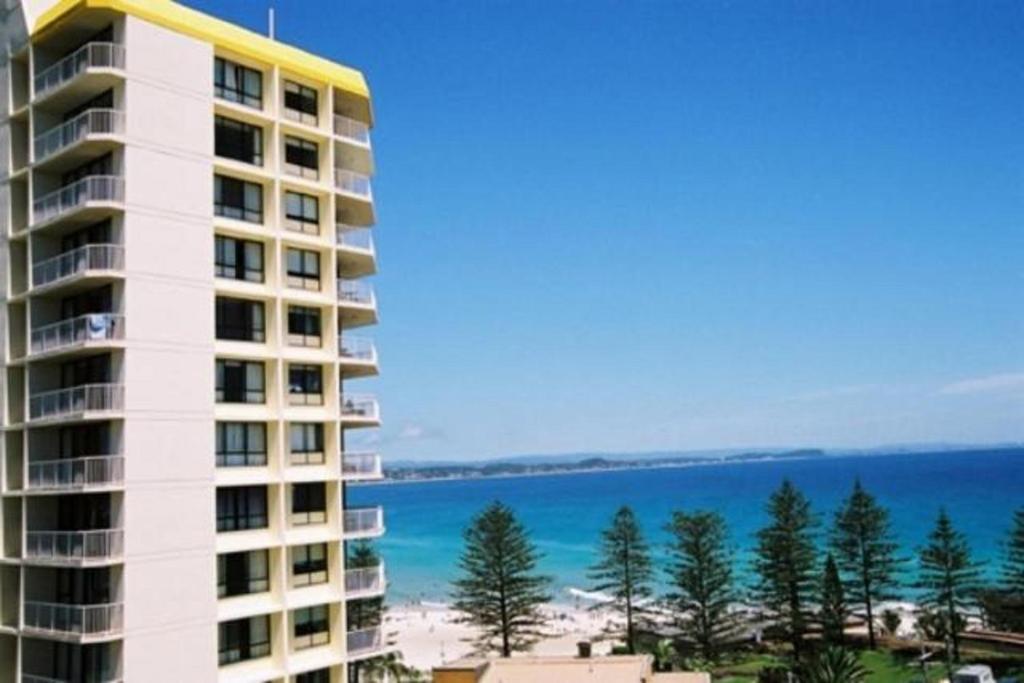 a tall building with the ocean in the background at Carool Holiday Apartments in Gold Coast