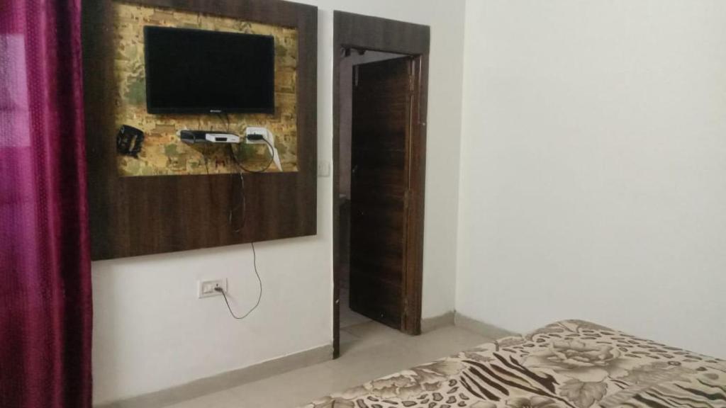 a bedroom with a bed and a television on a wall at Hotel Vanya Palace By WB Inn in Agra