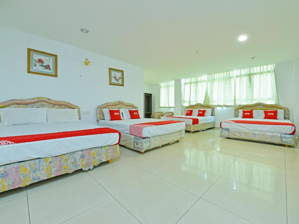 a large room with four beds in it at Super OYO 90494 Sam Huat Hotel in Kampong Atap