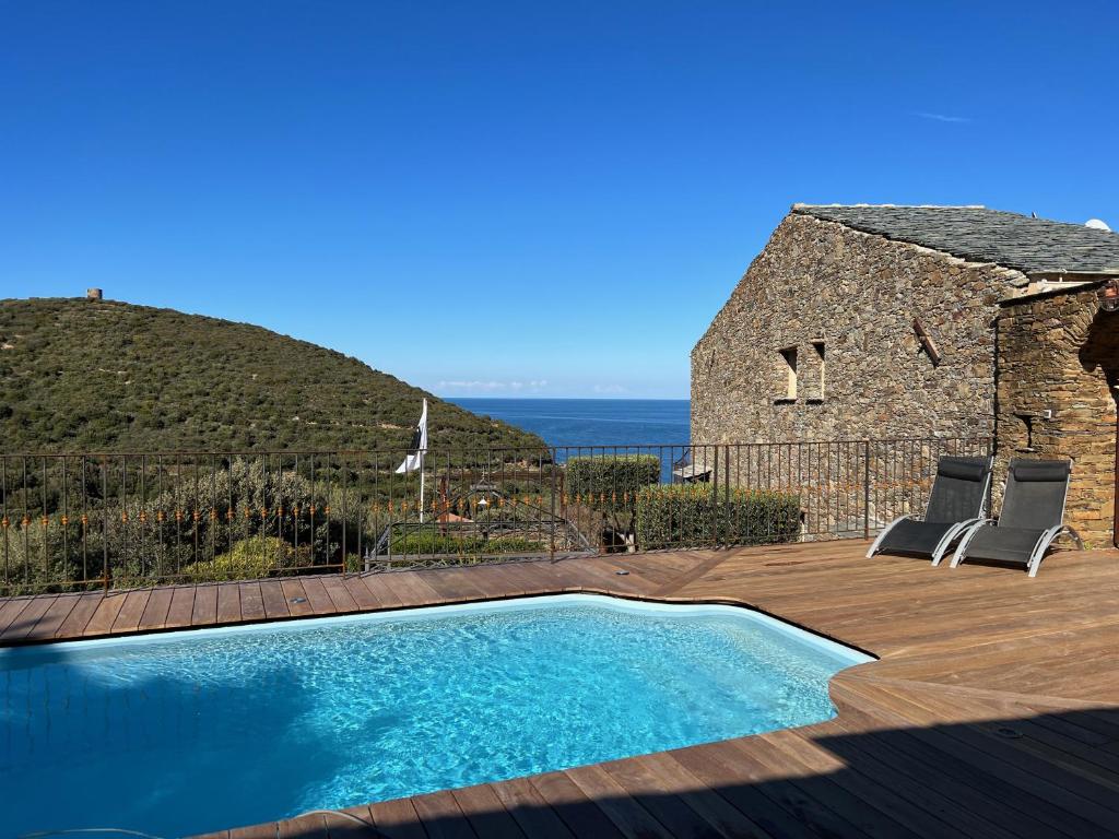 a swimming pool with two chairs and a building at Casa di Babbo in Macinaggio