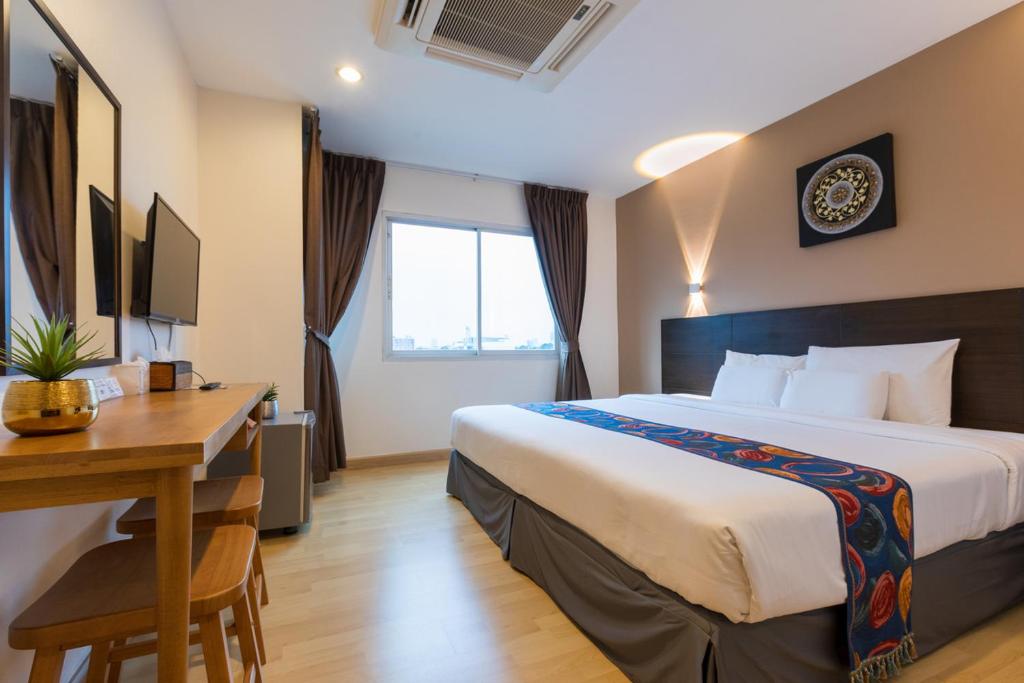 Habitación de hotel con cama y escritorio en 24@Home Hotel, en Nonthaburi