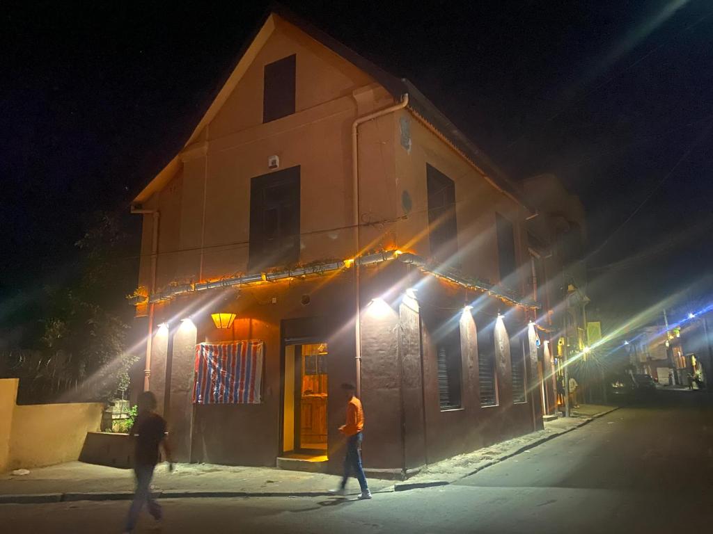 dos personas caminando en frente de un edificio por la noche en La Casa Blu, en Antananarivo