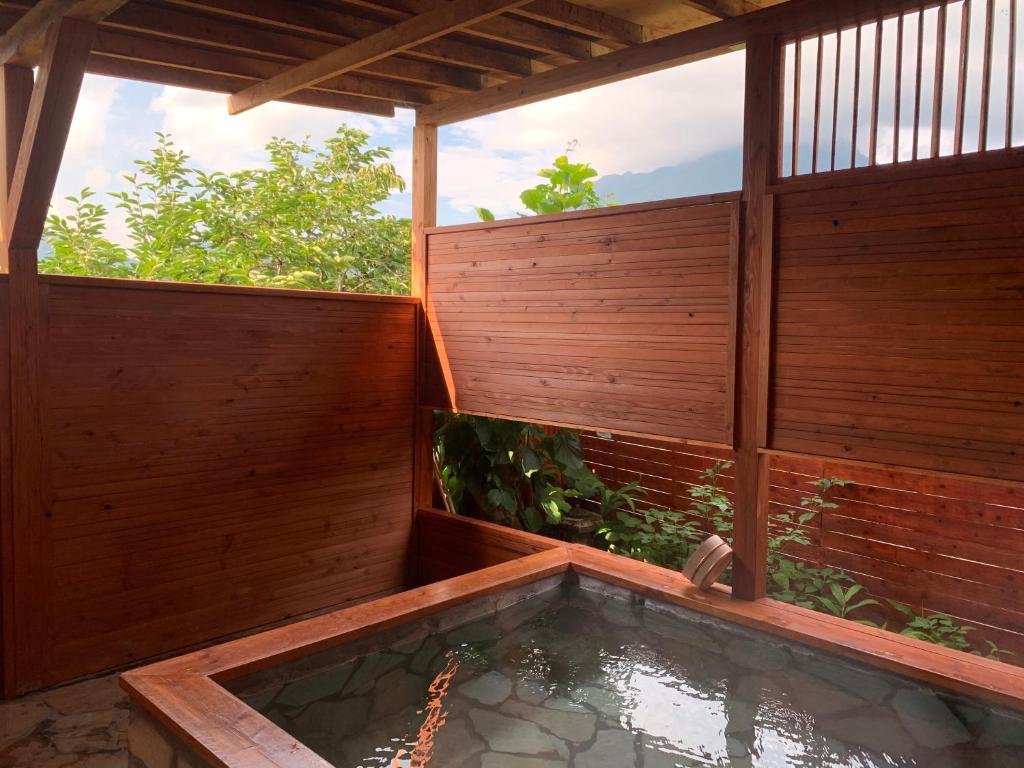 una bañera de hidromasaje en un patio trasero con una valla de madera en Yufuin Sunday, en Yufu