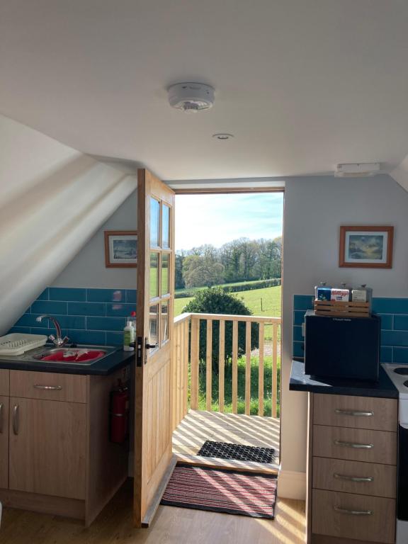 eine Küche mit einer Tür, die auf einen Balkon führt in der Unterkunft Barn Flat overlooking beautiful Dorset vale in Sherborne