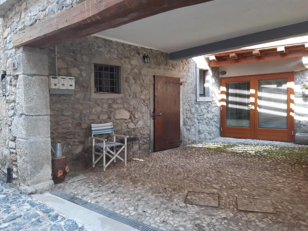 Casa de piedra con puerta de madera y silla en Mountain Lodge, en Raveo