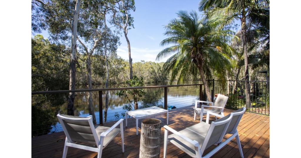 a deck with chairs and a table next to a body of water at The Lake House - Cabarita Beach in Cabarita Beach