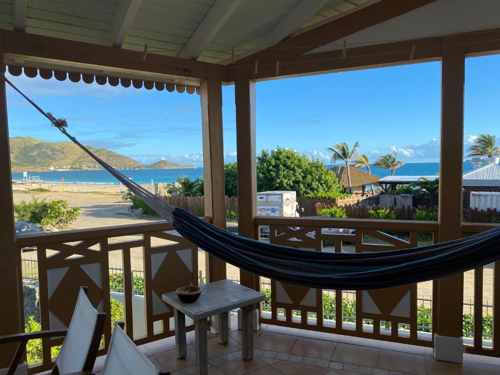 eine Hängematte auf einer Veranda mit Blick auf den Strand in der Unterkunft Lovely one bedroom holiday home by the beach in Orient Bay