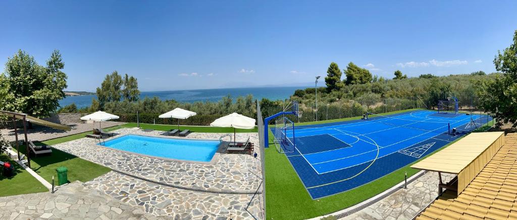 a swimming pool with a tennis court on a field at Rouga Paradise Resort in Vonitsa