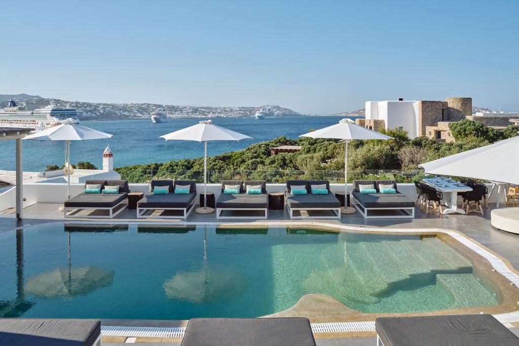 a swimming pool with lounge chairs and umbrellas at Mykonos Princess Hotel in Agios Stefanos