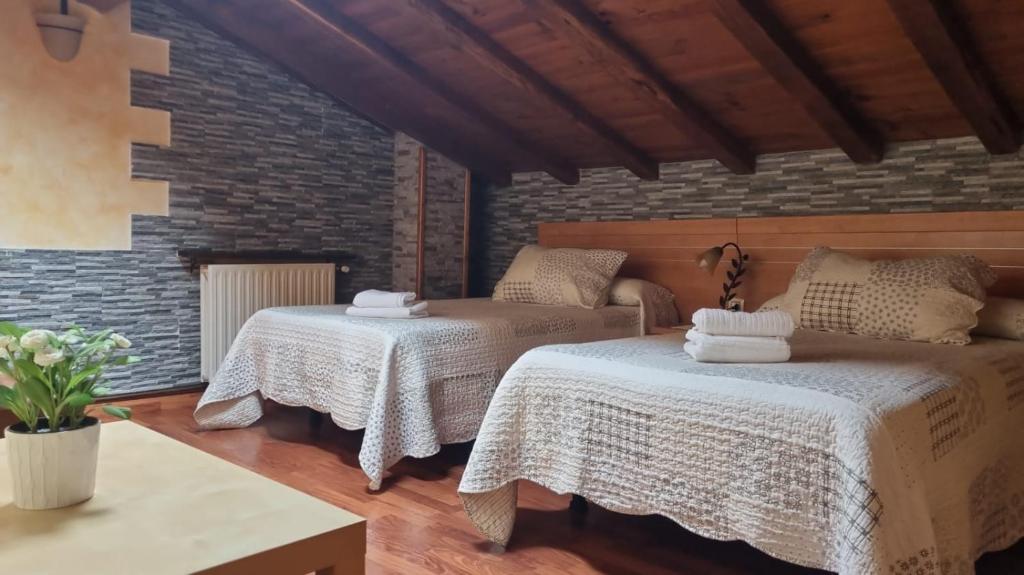 a bedroom with two beds and a brick wall at Casa Cuevas in Cuevas