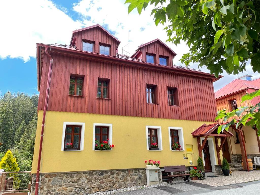ein gelbes und rotes Haus mit rotem Dach in der Unterkunft Penzion Pohádka in Železná Ruda