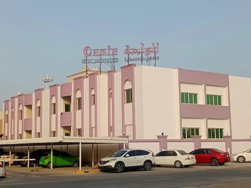 un edificio con coches estacionados frente a él en Oasis Hotel Apartment, en Ras al Khaimah