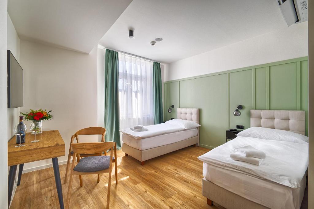 a bedroom with two beds and a desk and a table at Luma Terra Prague Hostel in Prague