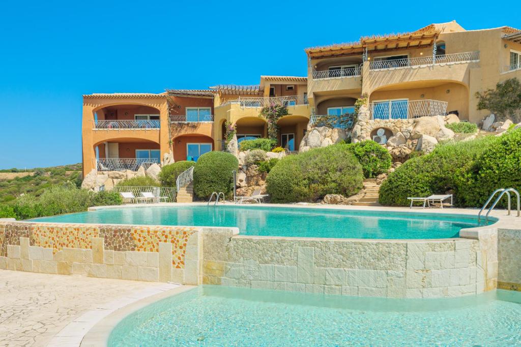 un resort con piscina di fronte a un edificio di Appartamento Smeralda - SHERDENIA Luxury Apartments a Marinella
