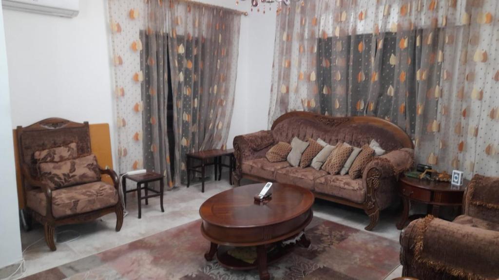 a living room with a couch and a table and chairs at Cool Bayader apartment in Amman