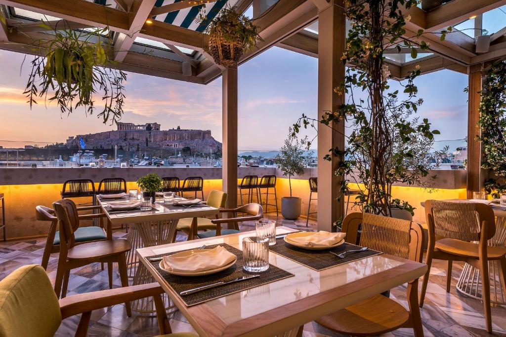 a restaurant with tables and chairs and a view of the city at Niche Hotel Athens in Athens