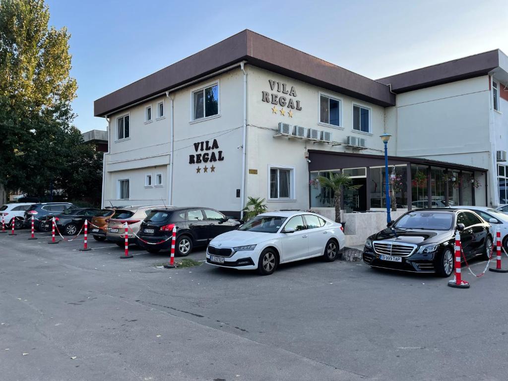 a parking lot with cars parked in front of a building at VILA REGAL Mamaia in Mamaia