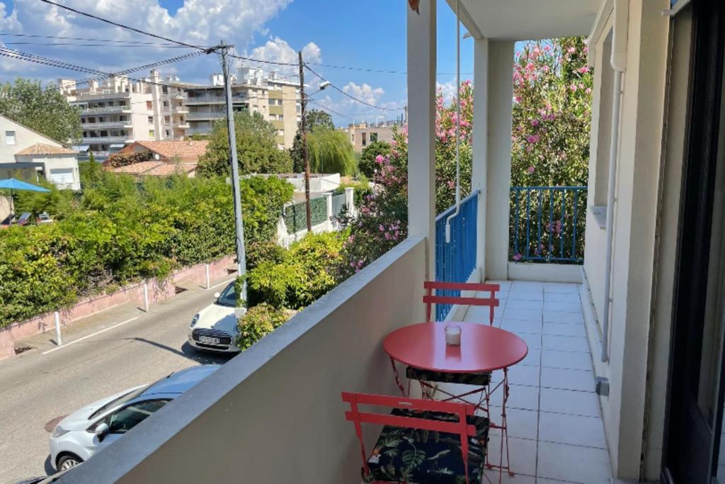 une table rouge sur un balcon avec vue sur une rue dans l'établissement Studio For 2 People Near The Beach Of Antibes, à Antibes