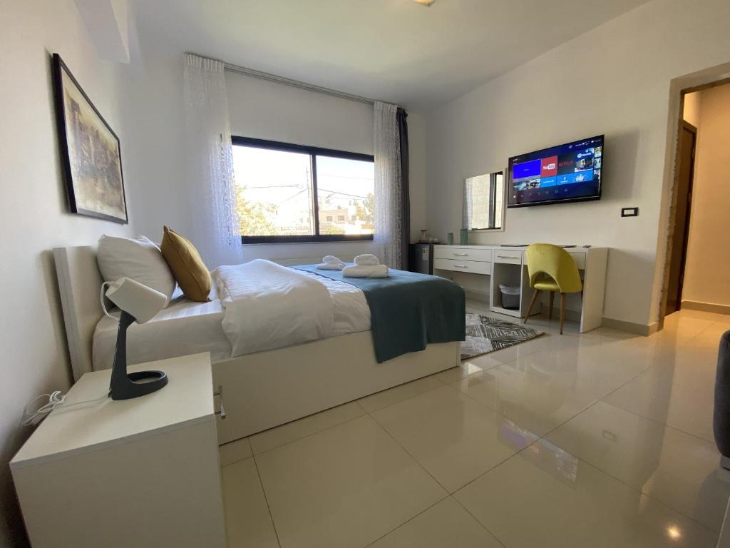 a bedroom with a bed and a desk and a tv at Lemon Tree Residence in Amman