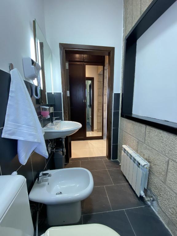 a bathroom with a white toilet and a sink at Lemon Tree Residence in Amman