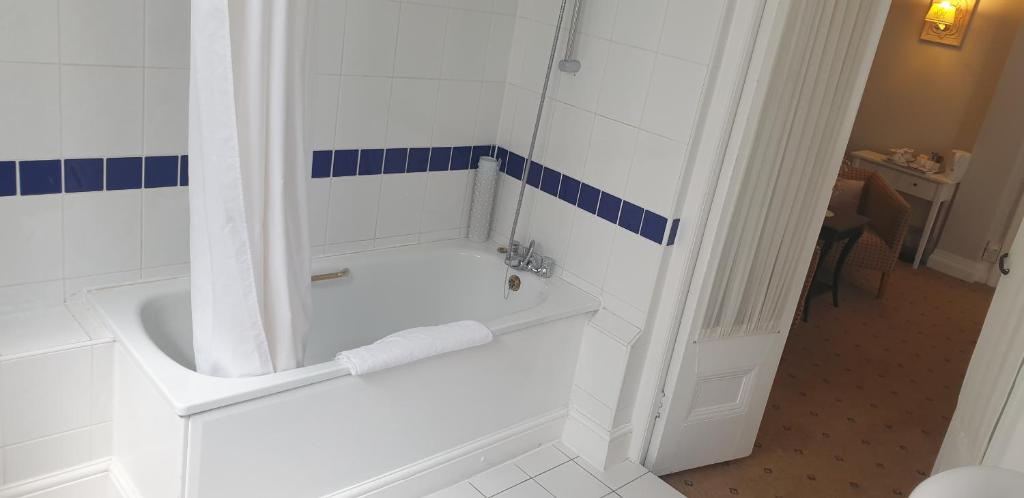 a white bathroom with a tub and a shower at The Tudor Hotel in Harrow