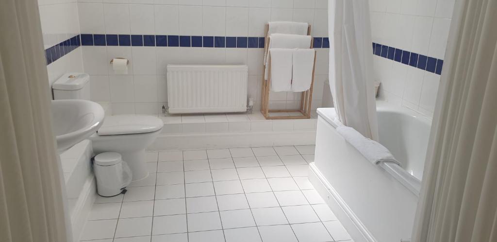 a white bathroom with a toilet and a sink at The Tudor Hotel in Harrow