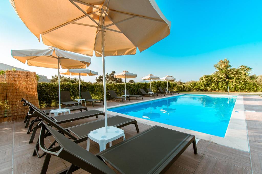 a pool with chairs and umbrellas and a swimming pool at Koulouris Apartments & Studios in Kalyves