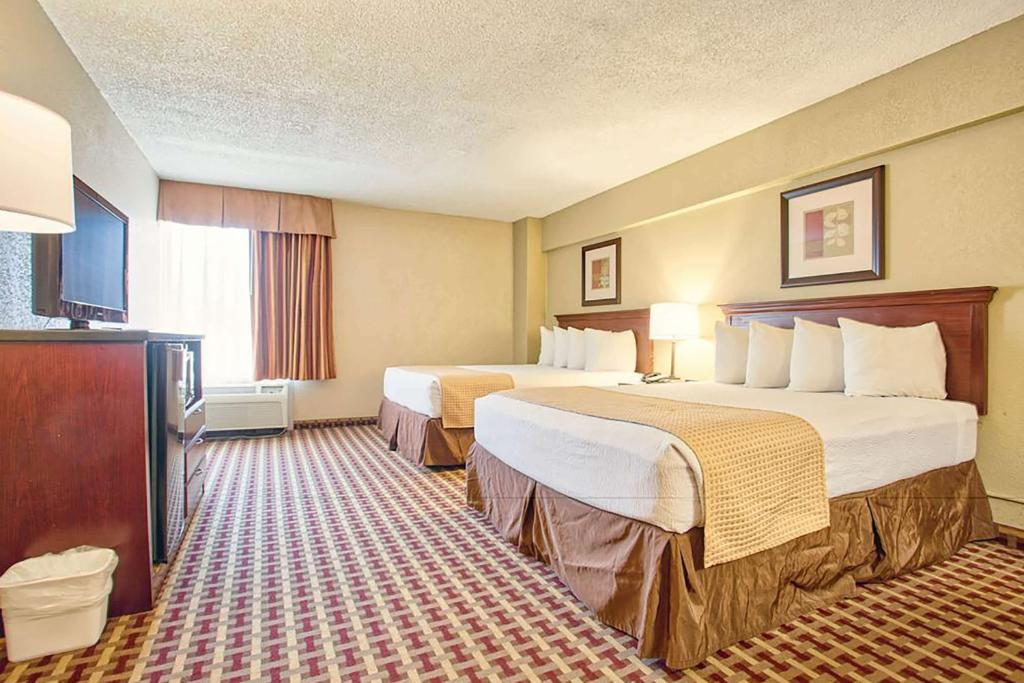 a hotel room with two beds and a television at Days Inn & Suites by Wyndham Johnson City in Johnson City