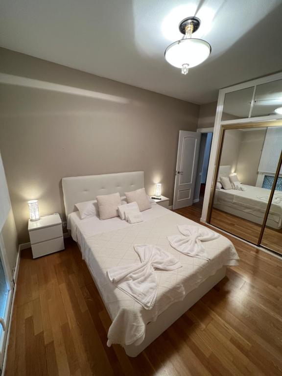 a bedroom with a large white bed and a mirror at Apartamento Elena Tour in Logroño