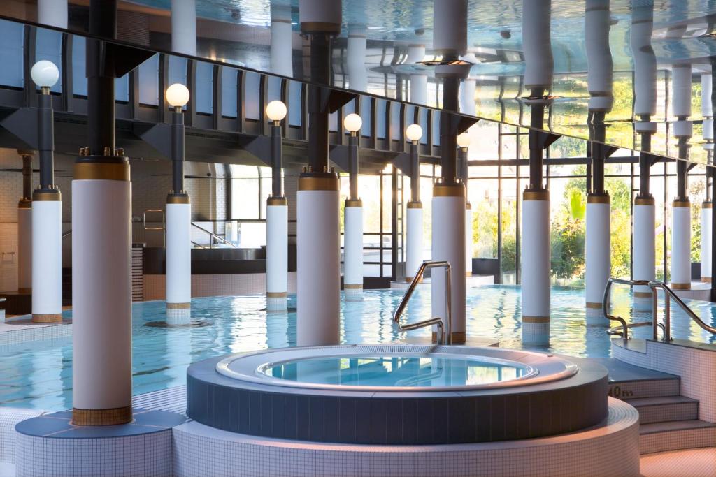 a large pool with a hot tub in the middle of a building at Victoria Jungfrau Grand Hotel & Spa in Interlaken