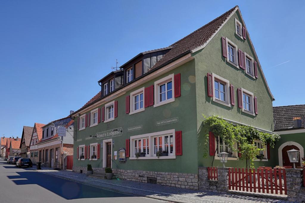 美茵河畔施瓦爾察赫的住宿－Ferienhaus Schwab - Sauna, eigene Terrasse, 3 Schlafzimmer - by homekeepers，街道上带红色窗户的绿色建筑