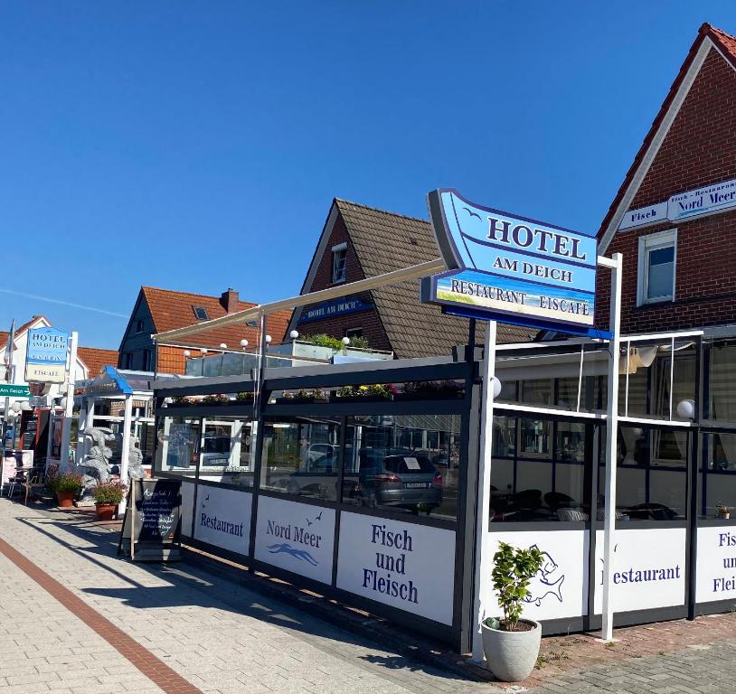 a building with a hotel sign on a street at Hotel Am Deich in Norddeich