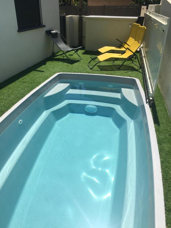 a swimming pool in a yard with two chairs at Lou Mazet in Uchaud
